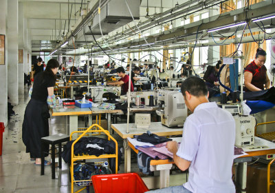 民营新秀·华亨服饰厂的工人们在用机车缝制衣服