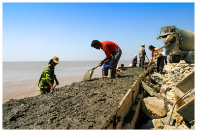 2005年9月24日,骄阳下的霓屿海堤工地，建设者们挥汗如雨与潮汐赶时间。