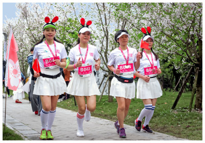 五：欢乐跑队员在樱花盛开的小路上地欢快地跑过。