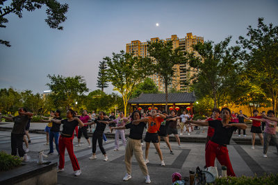 市民们晚饭后在公园做各种健身活动的场面，生活的幸福感。