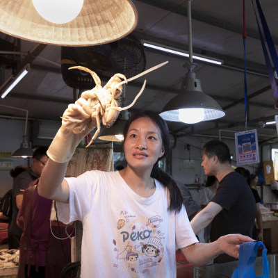 一位摊主正在给顾客挑选猷蛑