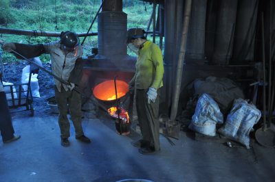 青山、绿水、古宅环抱的熔铝点，工人将熔化的高温铝水舀出。